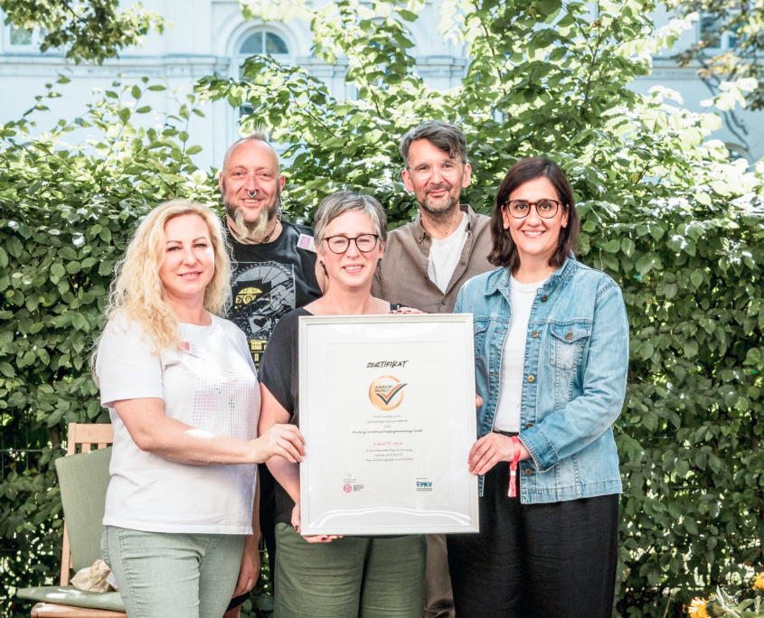 Beim Hospiz-Sommerfest 2025 wird das Siegel "Liebensort Vielfalt" an unser Hospiz übergeben. Melanie, Michael, Henrik und Alina von Hamburg Leuchtfeuer nehmen das Siegel entgegen. Senatorin Maryam Blumenthal ist bei der Übergabe dabei.