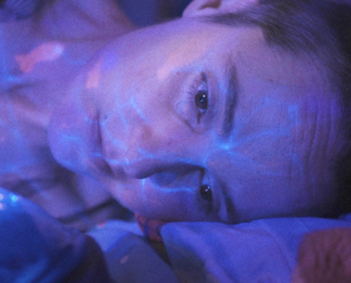 Aufnahme aus "Ich sterbe. Kommst Du?": Nadines Gesicht ins in blaues und lila Licht getaucht.