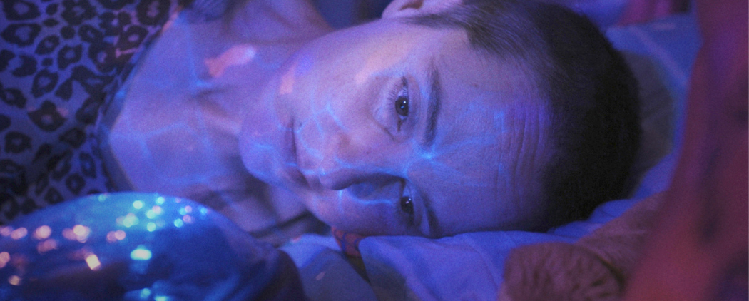 Aufnahme aus "Ich sterbe. Kommst Du?": Nadines Gesicht ins in blaues und lila Licht getaucht.
