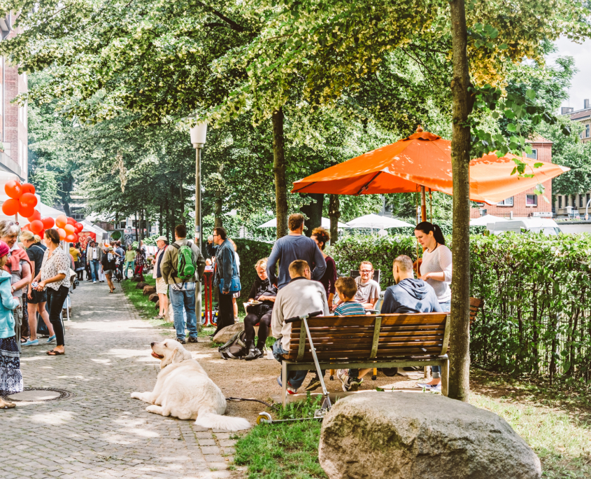 Vor dem Hamburg Leuchtfeuer Hospiz sind viele Stände und ein Flohmarkt aufgebaut. Bei sommerlichem Wetter sind viele Menschen unterwegs.