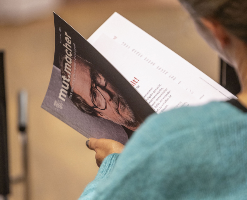 Hamburg Leuchtfeuer InfoVeranstaltung Vorsorge und Testament Frau liest mut.macher-Magazin von Hamburg Leuchtfeuer.